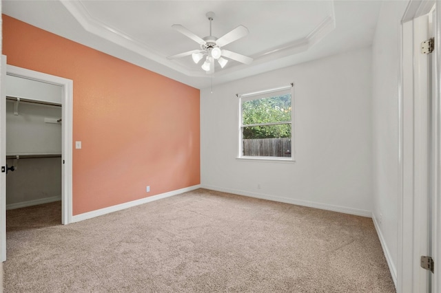 spare room featuring carpet, a raised ceiling, a ceiling fan, and baseboards