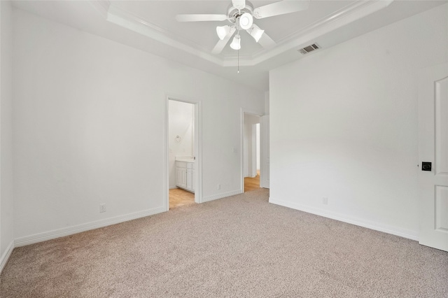 unfurnished bedroom with light carpet, baseboards, visible vents, ensuite bathroom, and a tray ceiling