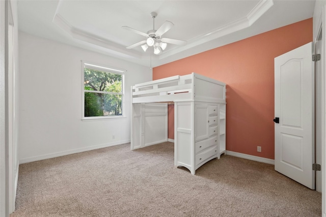 unfurnished bedroom featuring light carpet, baseboards, a tray ceiling, and ceiling fan