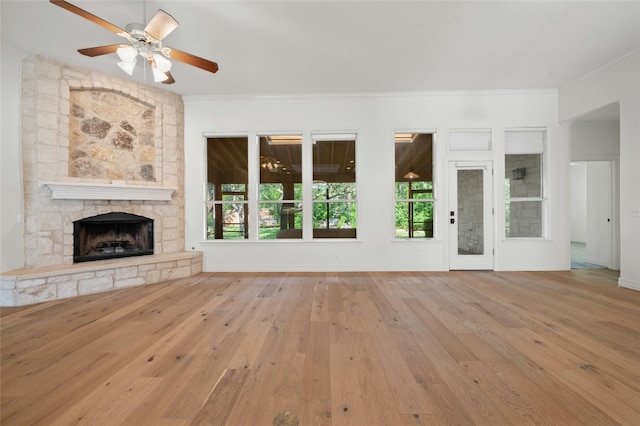 unfurnished living room with a fireplace, hardwood / wood-style floors, ornamental molding, ceiling fan, and baseboards