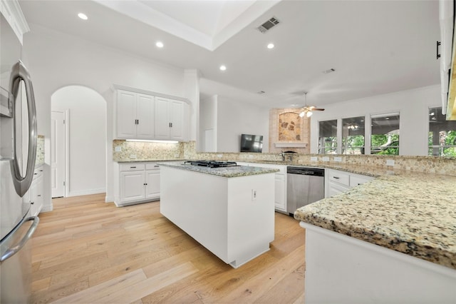 kitchen featuring tasteful backsplash, visible vents, arched walkways, light wood-style flooring, and stainless steel appliances