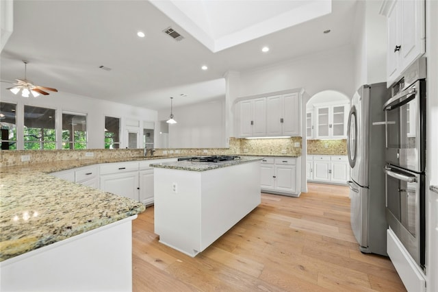 kitchen with light wood finished floors, visible vents, stainless steel appliances, and decorative backsplash