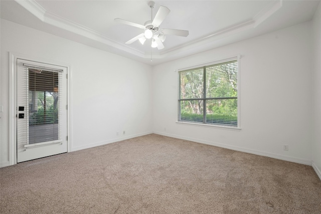 unfurnished room with plenty of natural light, a tray ceiling, carpet flooring, and ornamental molding