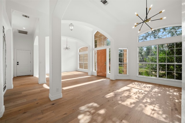 entrance foyer with a towering ceiling, hardwood / wood-style flooring, visible vents, and a notable chandelier