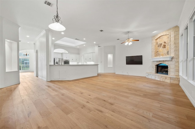 unfurnished living room with visible vents, ceiling fan with notable chandelier, light wood-type flooring, a fireplace, and recessed lighting