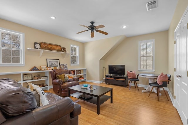 living room featuring baseboards, light wood-type flooring, visible vents, and recessed lighting