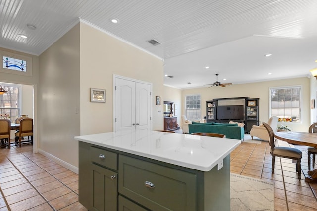 kitchen with a center island, light tile patterned floors, visible vents, ornamental molding, and green cabinetry