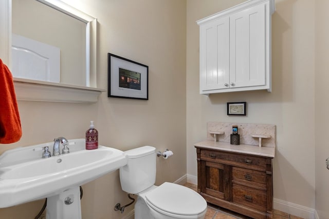 bathroom featuring tile patterned flooring, baseboards, a sink, and toilet