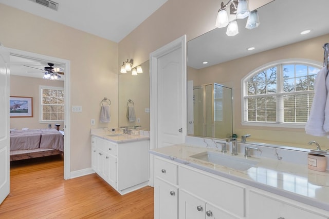 full bath with a stall shower, plenty of natural light, a sink, and wood finished floors