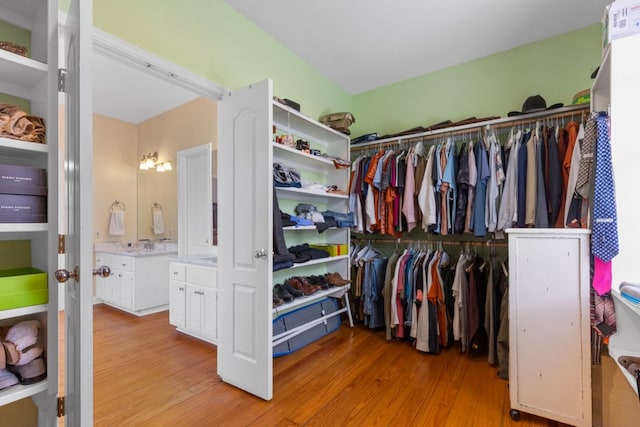 walk in closet with a sink and wood finished floors