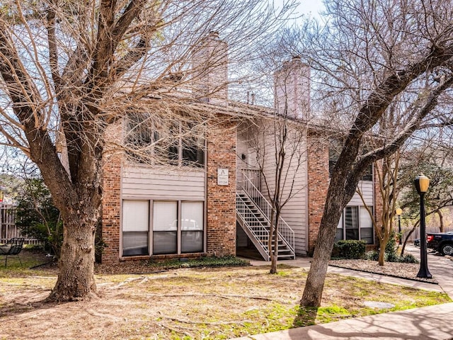 view of front of property with stairs, brick siding, and a chimney