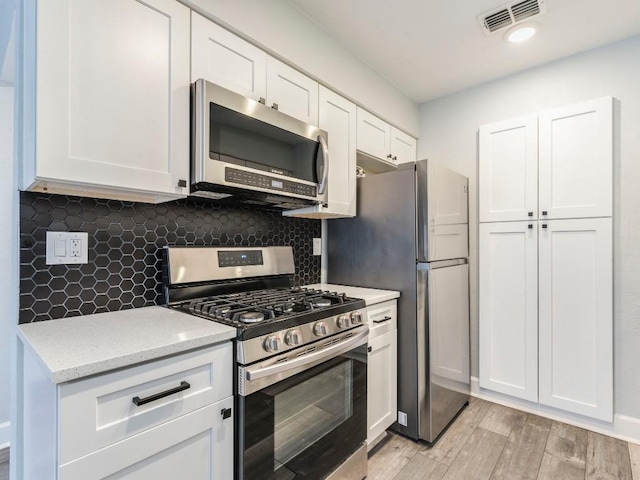 3839 Dry Creek Dr Unit 216, Austin, TX 78731 - kitchen with visible vents, light wood-style floors, white cabinetry, light stone counters, and appliances with stainless steel finishes