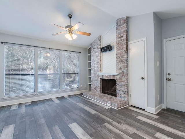 unfurnished living room with a ceiling fan, a brick fireplace, vaulted ceiling, and wood finished floors