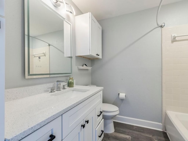 full bathroom with toilet, wood finished floors, vanity, baseboards, and washtub / shower combination