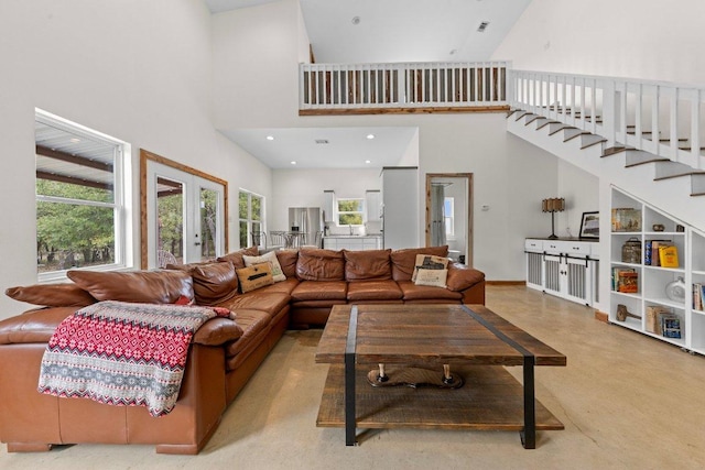 living area featuring french doors, concrete floors, a high ceiling, and stairs