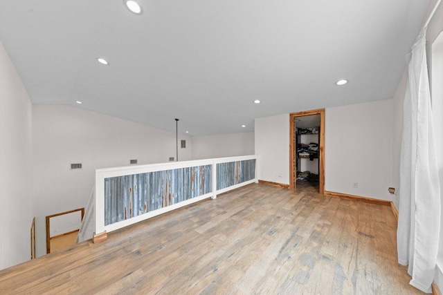 unfurnished room featuring recessed lighting, lofted ceiling, visible vents, wood finished floors, and baseboards