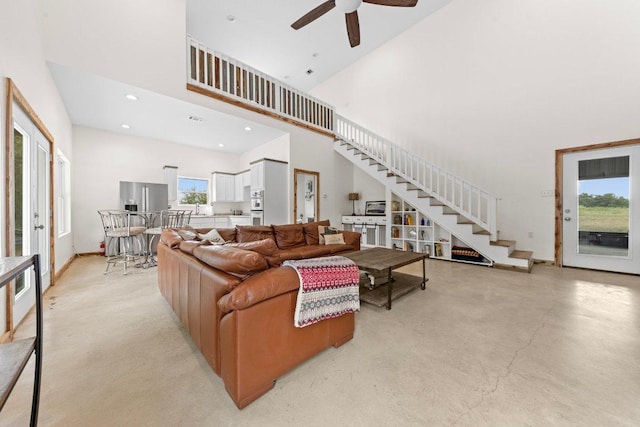 living room with recessed lighting, stairway, a high ceiling, concrete floors, and baseboards