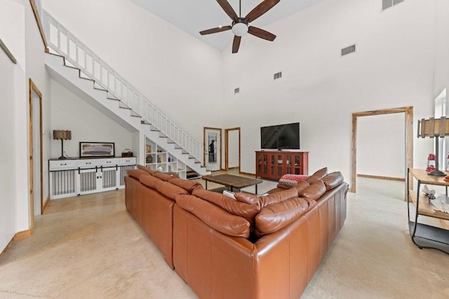 living area with visible vents, a high ceiling, and stairs