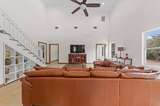 living area featuring visible vents, ceiling fan, a high ceiling, and stairs