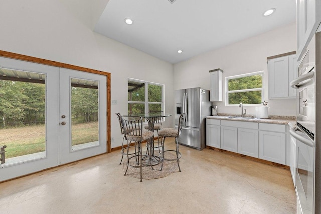 kitchen with finished concrete floors, stainless steel refrigerator with ice dispenser, a sink, and light countertops