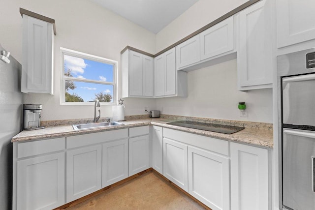 kitchen featuring white cabinets, stainless steel double oven, black electric cooktop, and a sink