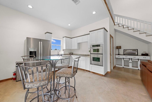 kitchen featuring baseboards, stainless steel appliances, concrete floors, white cabinetry, and recessed lighting