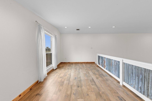 empty room featuring wood finished floors, visible vents, and baseboards