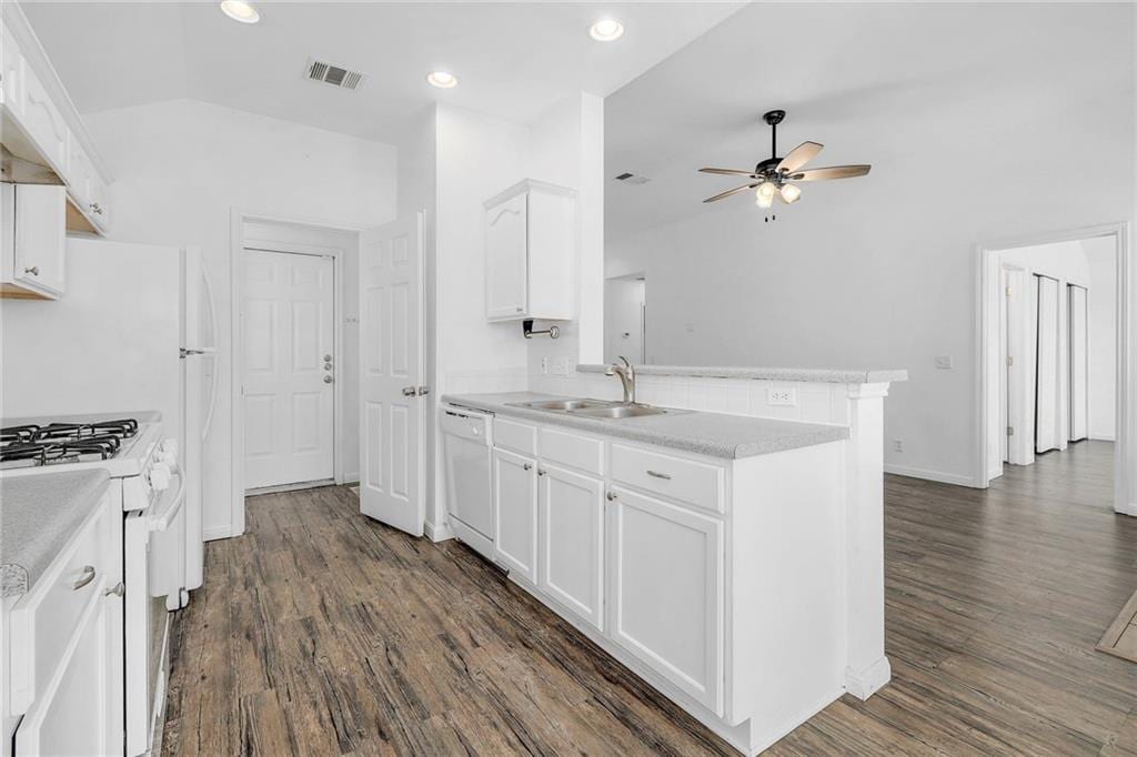 kitchen featuring visible vents, white cabinetry, a sink, white appliances, and a peninsula