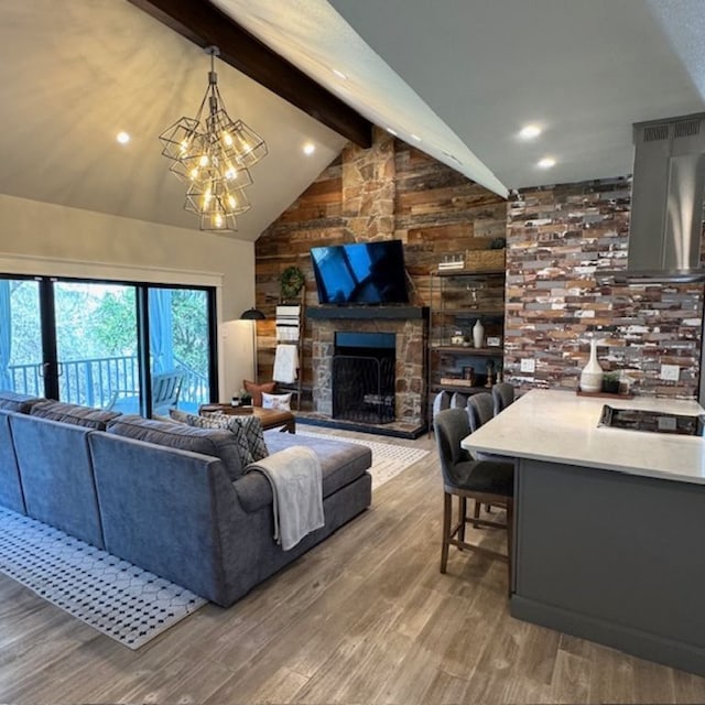 living room with beamed ceiling, wood finished floors, an inviting chandelier, a fireplace, and high vaulted ceiling