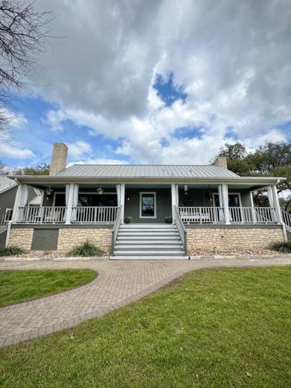 view of front facade with covered porch, metal roof, and a chimney