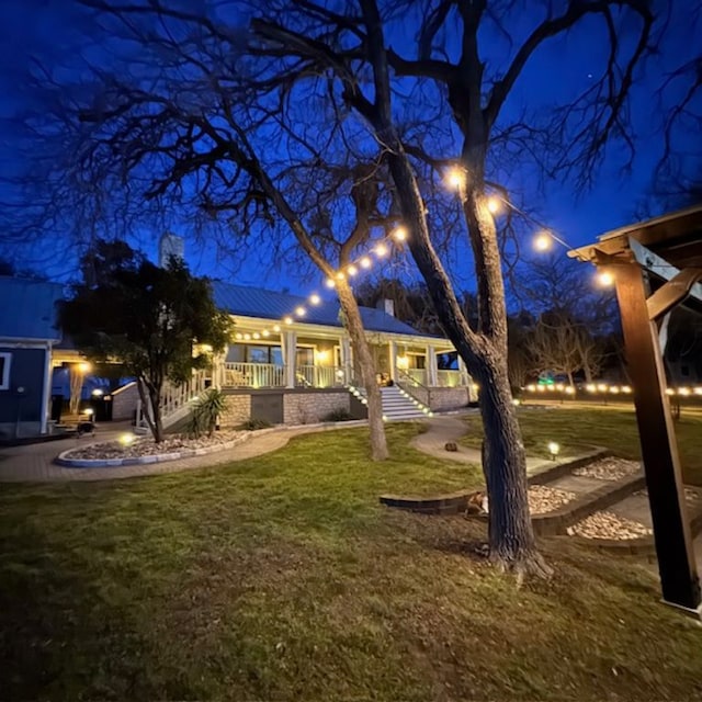 yard at night featuring a porch