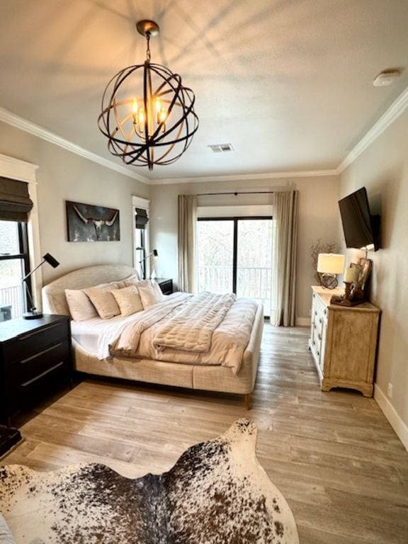 bedroom with a notable chandelier, wood finished floors, visible vents, baseboards, and crown molding