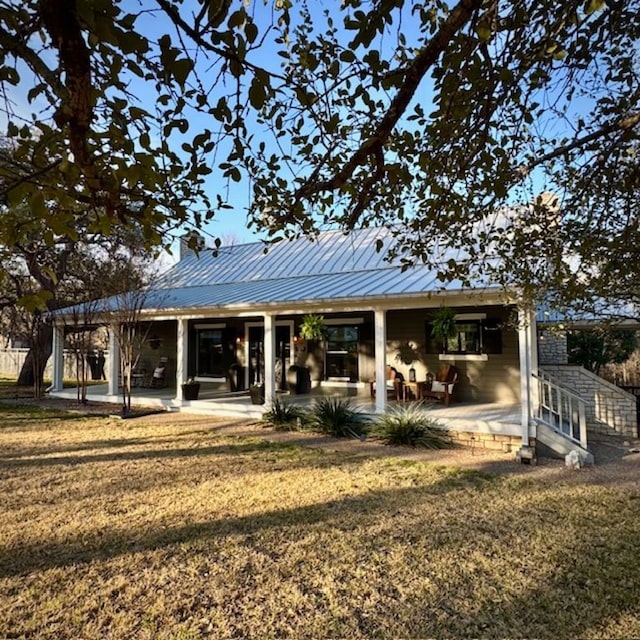 back of property with metal roof and a lawn