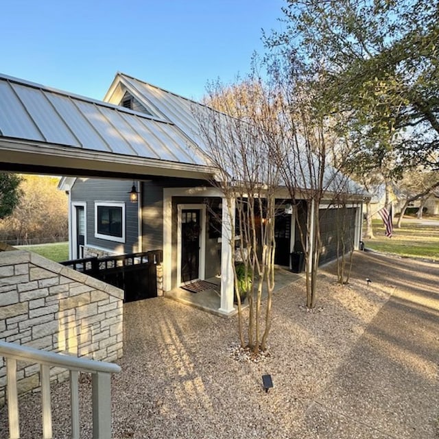 view of front facade with a standing seam roof, a patio area, and metal roof