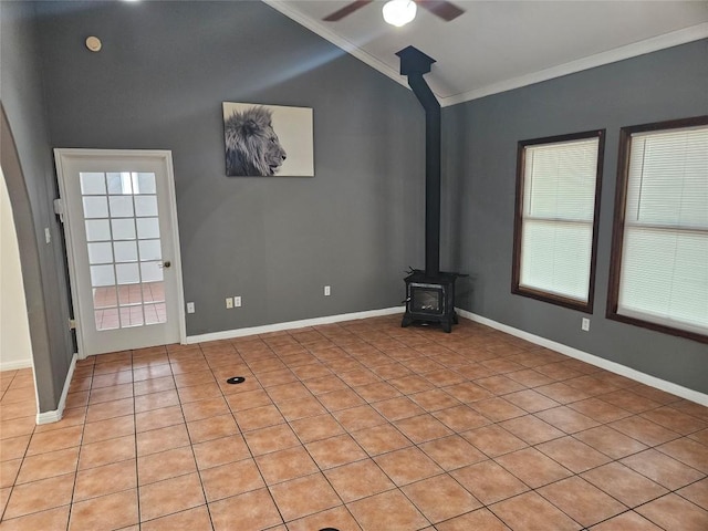 unfurnished living room featuring lofted ceiling, a ceiling fan, baseboards, a wood stove, and crown molding