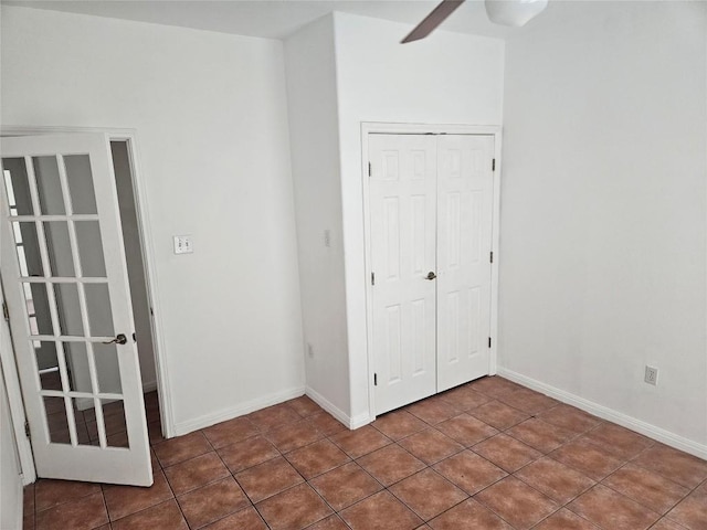 unfurnished bedroom with tile patterned flooring, a closet, and baseboards