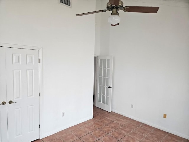 spare room featuring light tile patterned flooring, a ceiling fan, a towering ceiling, visible vents, and baseboards