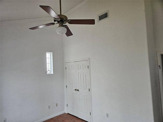 empty room with ceiling fan, baseboards, visible vents, and vaulted ceiling