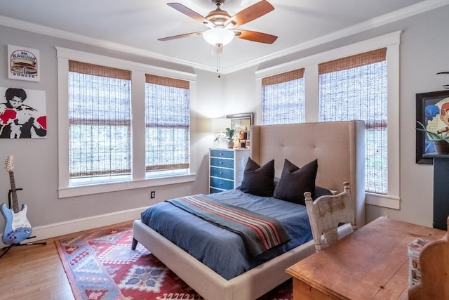 bedroom featuring a ceiling fan, crown molding, baseboards, and wood finished floors