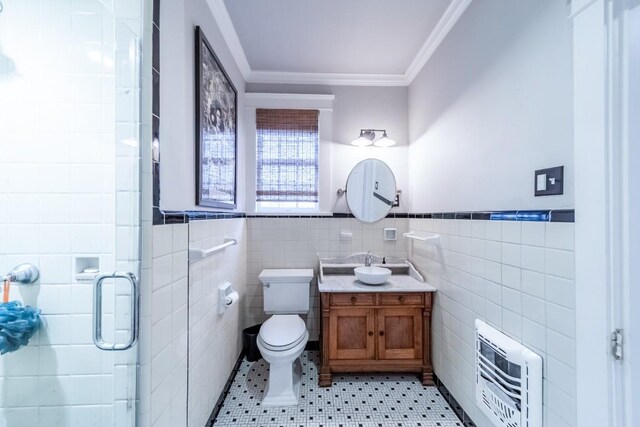 full bathroom featuring heating unit, toilet, ornamental molding, a shower stall, and vanity