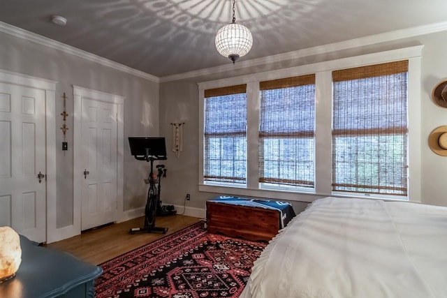 bedroom featuring baseboards, ornamental molding, and wood finished floors