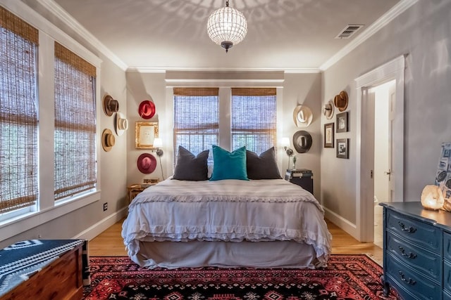 bedroom featuring ornamental molding, light wood-type flooring, visible vents, and baseboards