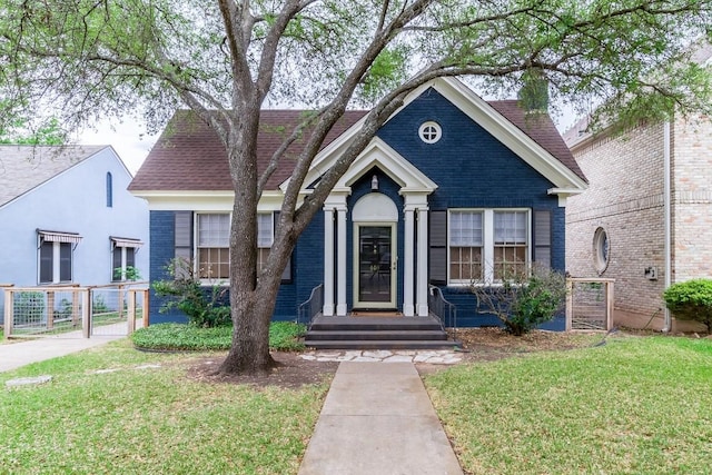 view of front of property featuring a shingled roof, a front yard, a gate, and brick siding