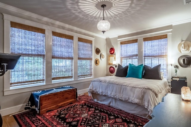 bedroom with ornamental molding, multiple windows, and wood finished floors