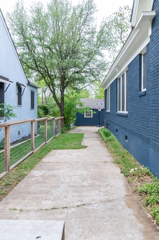 view of property exterior featuring an outbuilding, brick siding, fence, and a patio