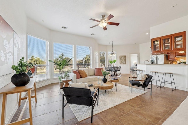 living room featuring ceiling fan, visible vents, and baseboards