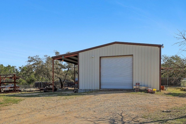 view of outbuilding with driveway, fence, and an outbuilding