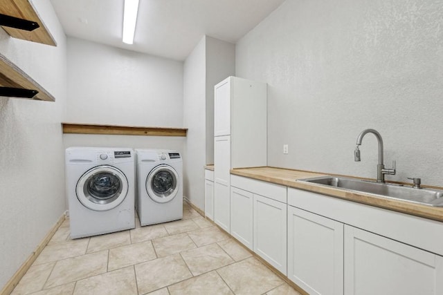 laundry area with baseboards, cabinet space, a sink, and washing machine and clothes dryer