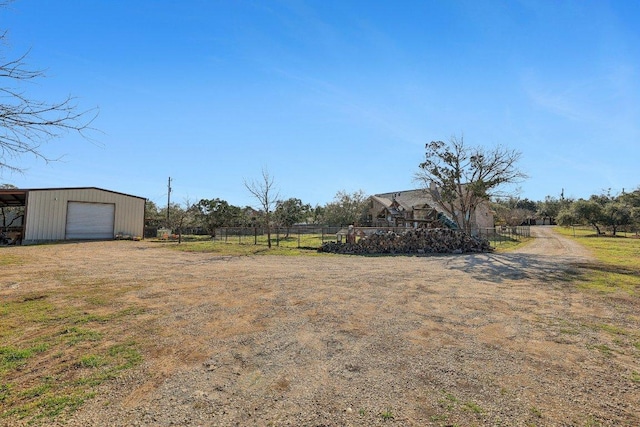 view of yard with driveway, a garage, an outbuilding, a pole building, and fence