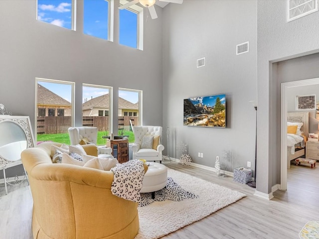 living room with visible vents, plenty of natural light, baseboards, and wood finished floors